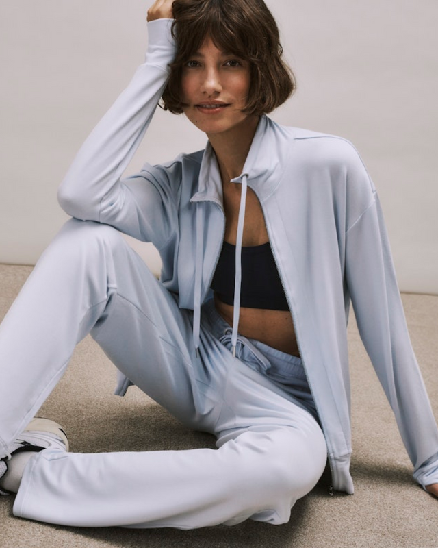 Woman in light blue Balance tracksuit sitting on the floor