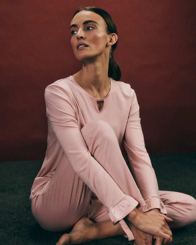 Woman wearing a pink Claire Pajama Set on the floor against a dark background