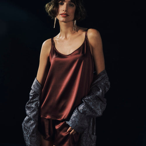 Woman wearing Grand Central Silk Camisole and Knickers in vivid brown with men's Selection robe falling off the shoulders