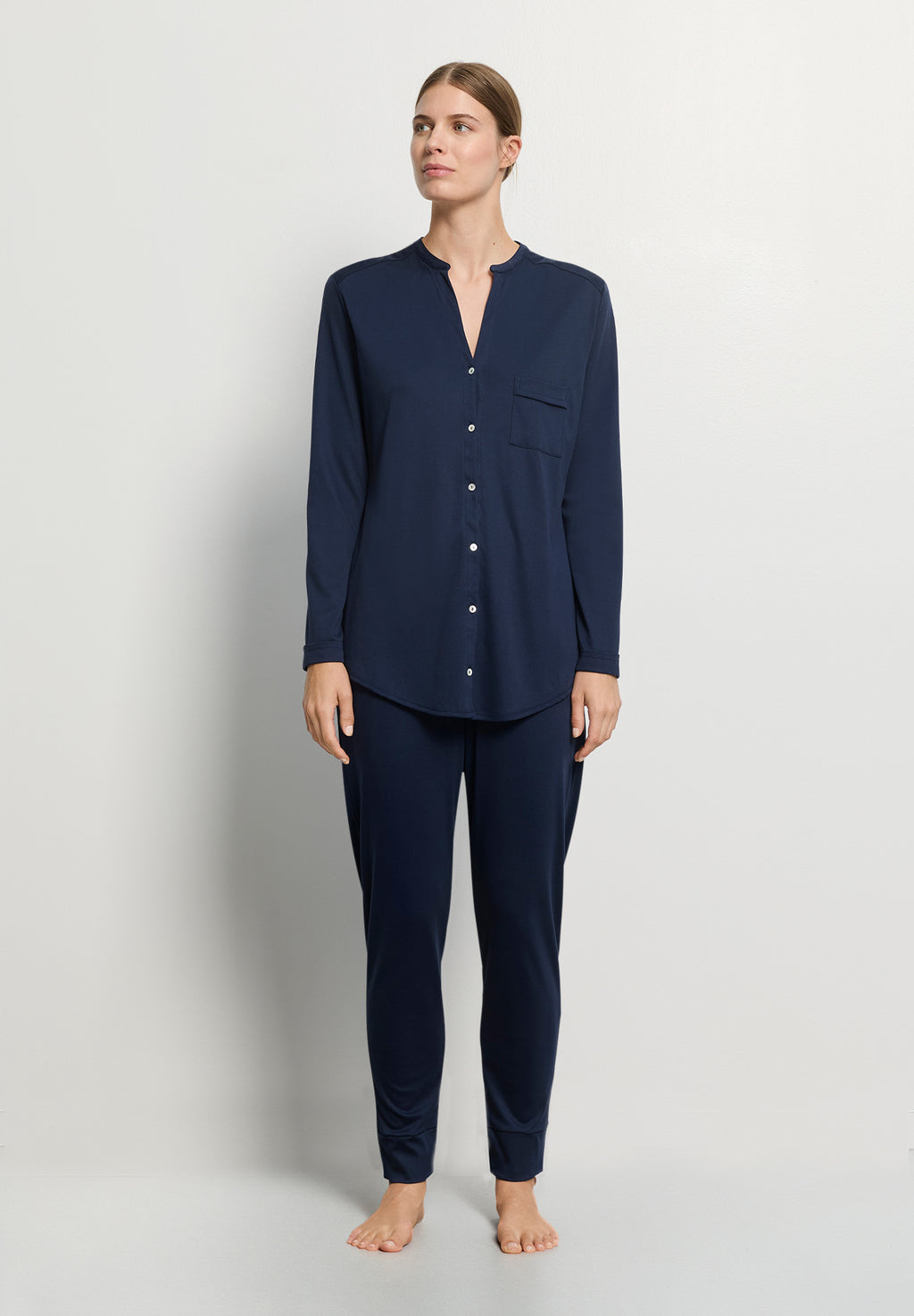 Person wearing navy blue pajamas on a light gray background