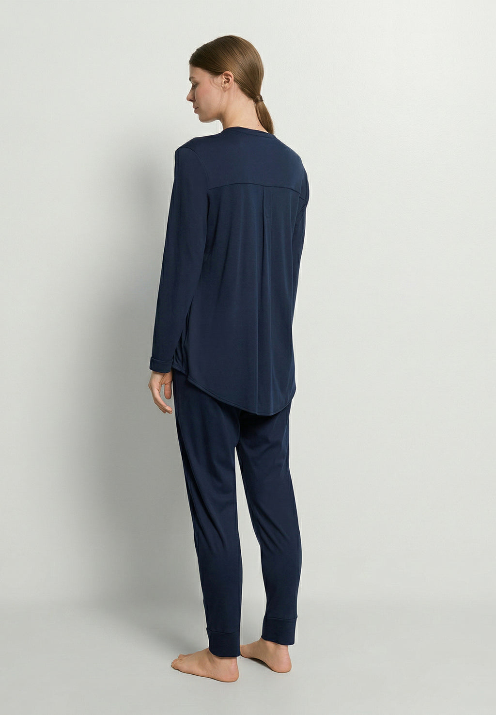 Person wearing a navy blue pajama set on a light gray background