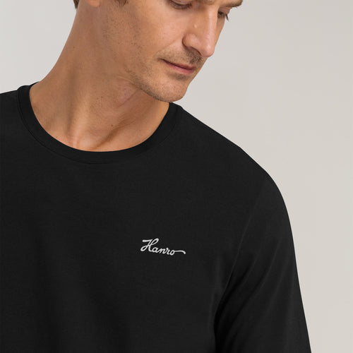 Man wearing a black t-shirt with 'Flavio' logo on a light gray background