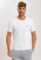 Man wearing a white t-shirt with a logo on a plain background