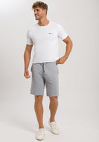Man wearing a white t-shirt and gray shorts on a plain background