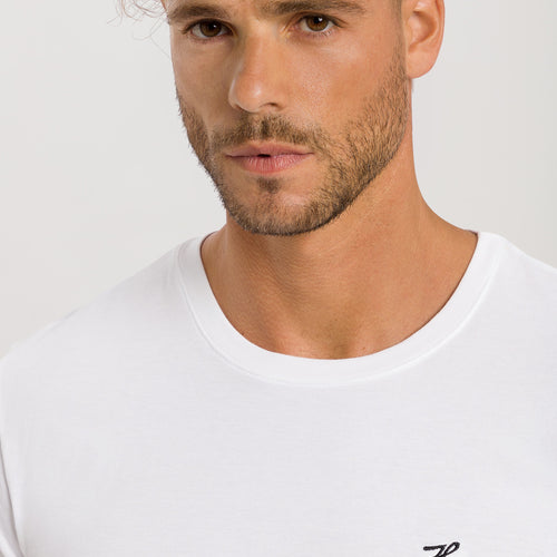 Man wearing a white t-shirt with branding on a light gray background
