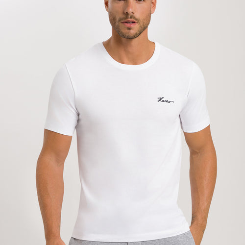 Man wearing a white t-shirt with a logo on a plain background