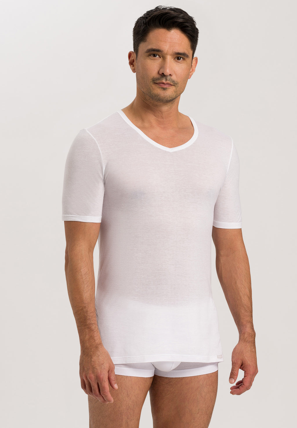 Man wearing a plain white t-shirt and underwear on a light gray background