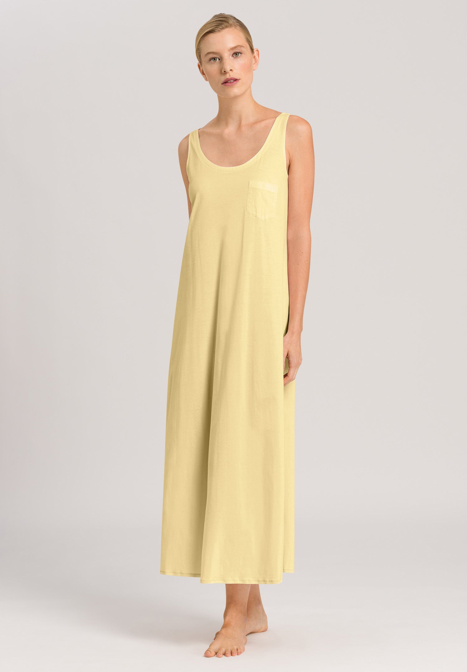 Woman wearing a yellow sleeveless dress on a plain background