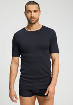 Man wearing a black t-shirt and underwear on a light gray background