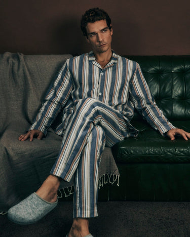 Man wearing cozy comfort striped pajamas sitting on a couch.