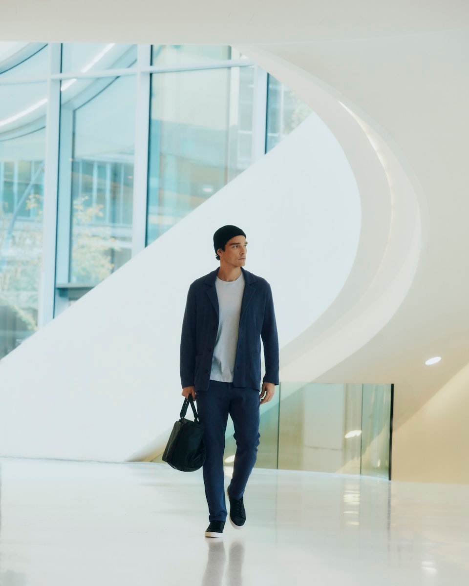 Man walking with a black bag in a modern building interior. Wearing Travelwear
