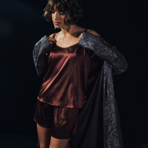 Woman wearing Grand Central Silk Camisole and Knickers in vivid brown with men's Selection robe
