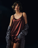 Woman wearing Grand Central Silk Camisole and Knickers in vivid brown with men's Selection robe falling off the shoulders