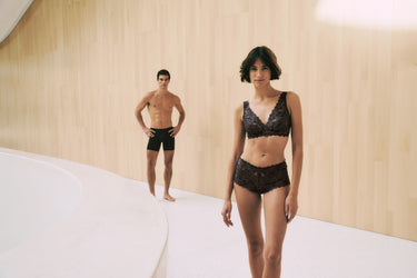Man and woman wearing black lingerie in a minimalistic room. Features Luxury Moments and Micro Touch