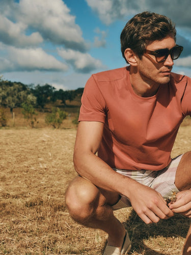 A man in a field wearing Living Shirts Cotton Crew Neck T-Shirt in Chutney paired with Night And Day Drawstring Cotton and Linen Shorts in Bluewood Stripe