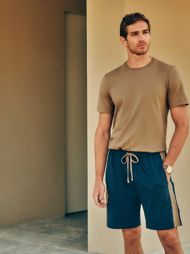Man standing outside with his hand in his pocket, wearing Living Shirts in Portabella Beige, paired with Night and Day Shorts.