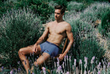 Man sitting among lavender plants wearing blue underwear.