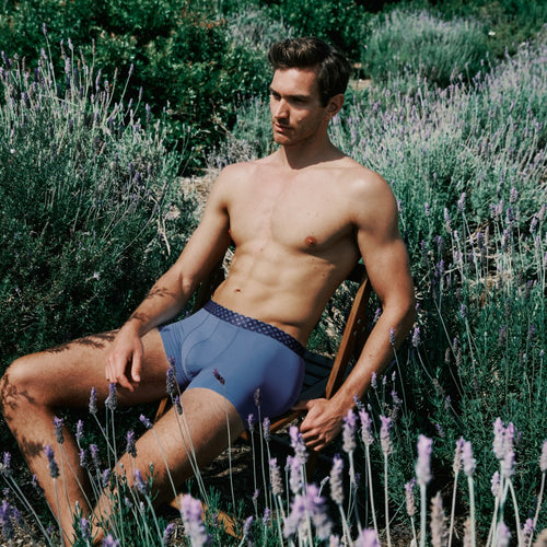 Man sitting among lavender plants wearing blue underwear.