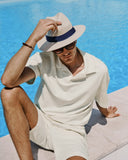 Person wearing a white outfit and hat by a pool