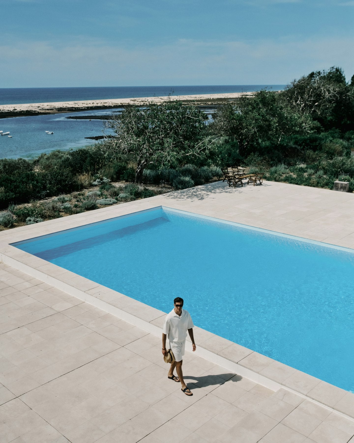 Man walking by a pool with a scenic ocean view