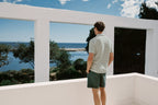 Man standing on a balcony overlooking a scenic view of water and trees.