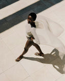 Woman walking on a tiled floor casting a shadow