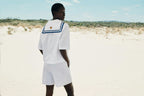 Person wearing a white outfit with a blue trim on the beach