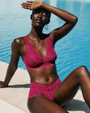 Woman in a pink lace bra and boyshort sitting by a pool