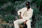 Person in a white outfit sitting on a chair surrounded by lavender plants