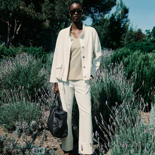 Person in a white outfit standing among lavender plants