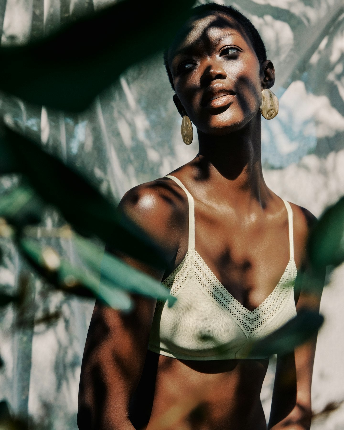 Woman wearing a white bikini top with greenery in the background