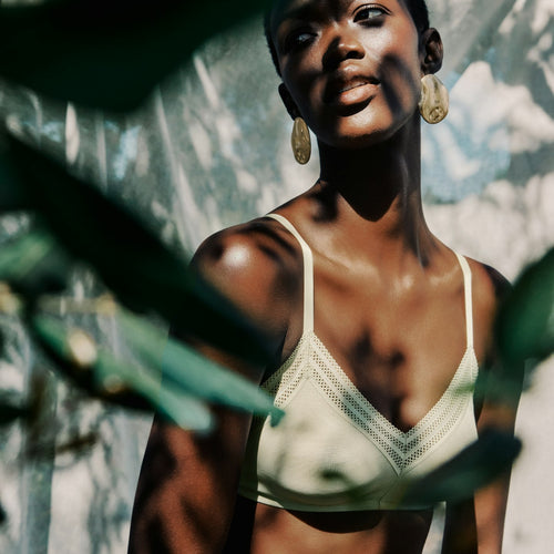 Woman wearing a white bikini top with greenery in the background
