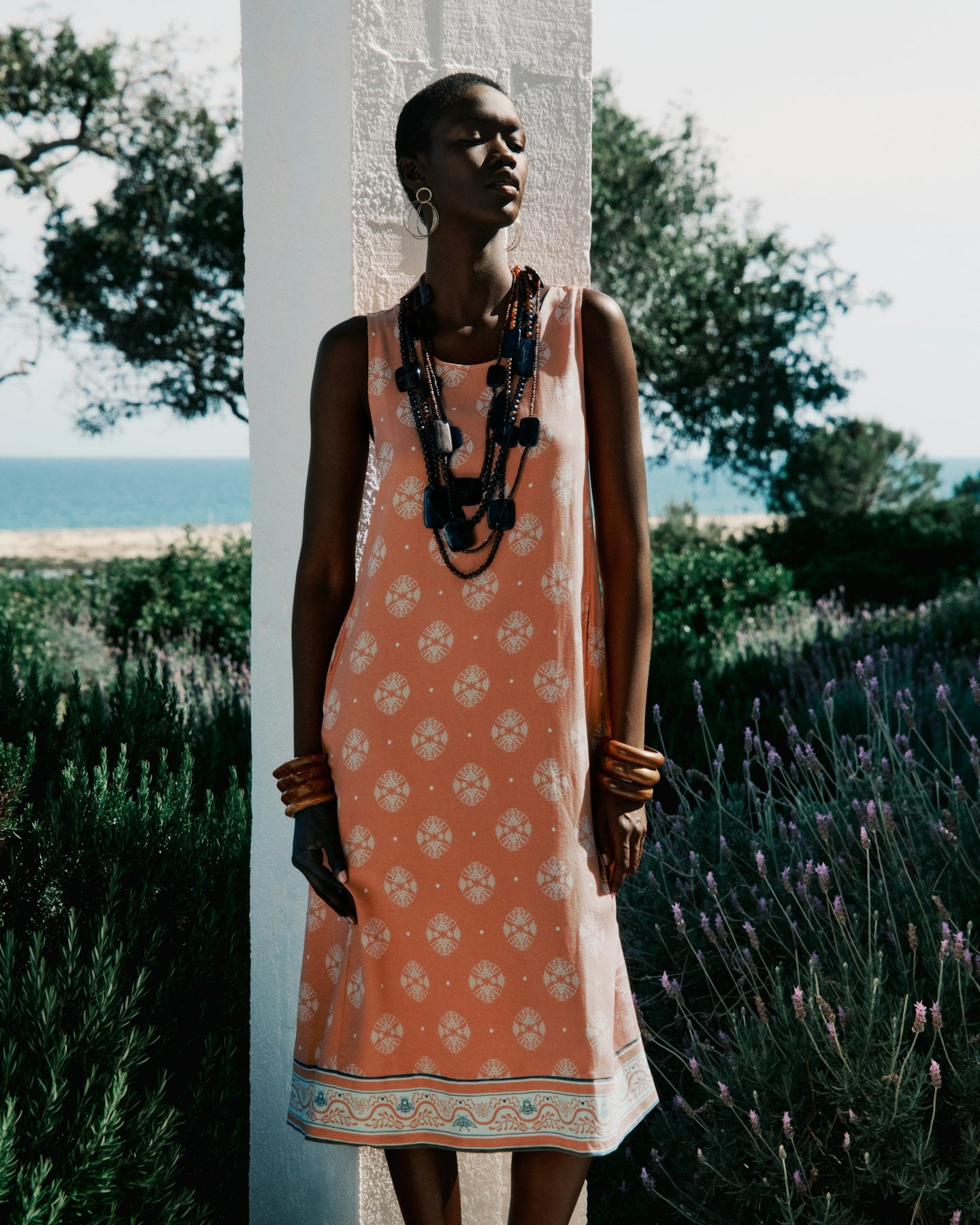 Woman in a patterned dress standing in a field with lavender and ocean view