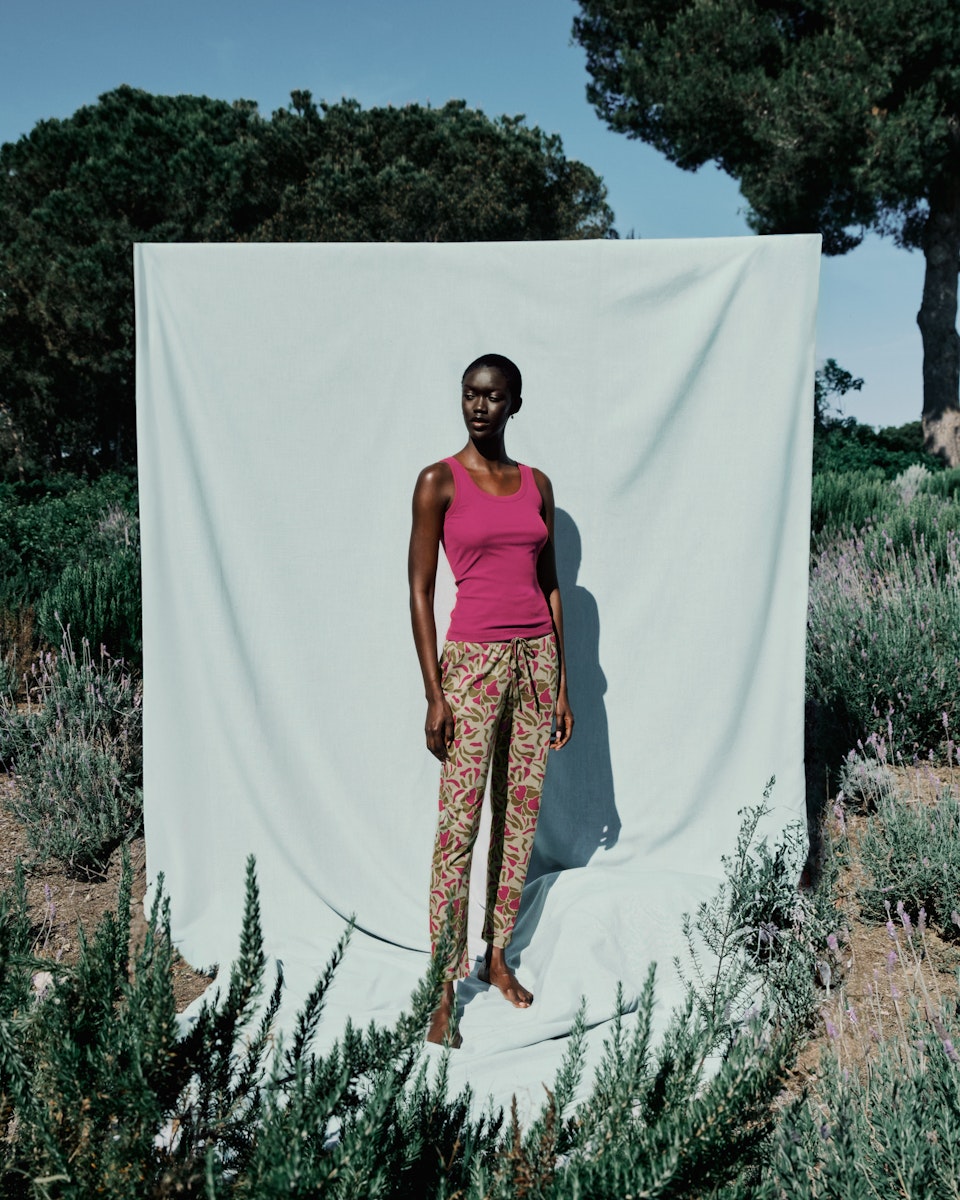 Woman standing in front of a white curtain outdoors with trees and plants around