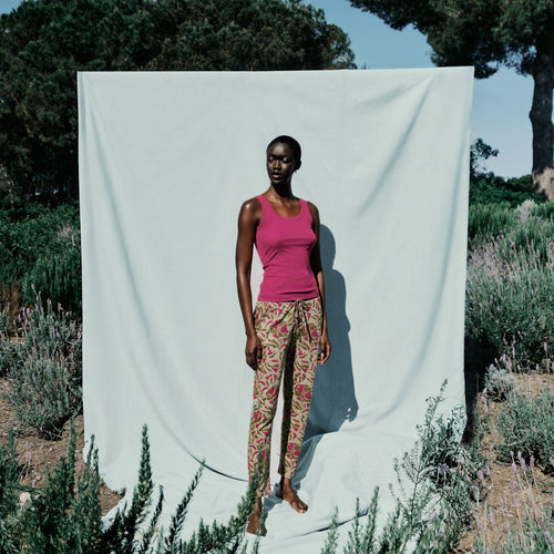 Woman standing in front of a white curtain outdoors with trees and plants around