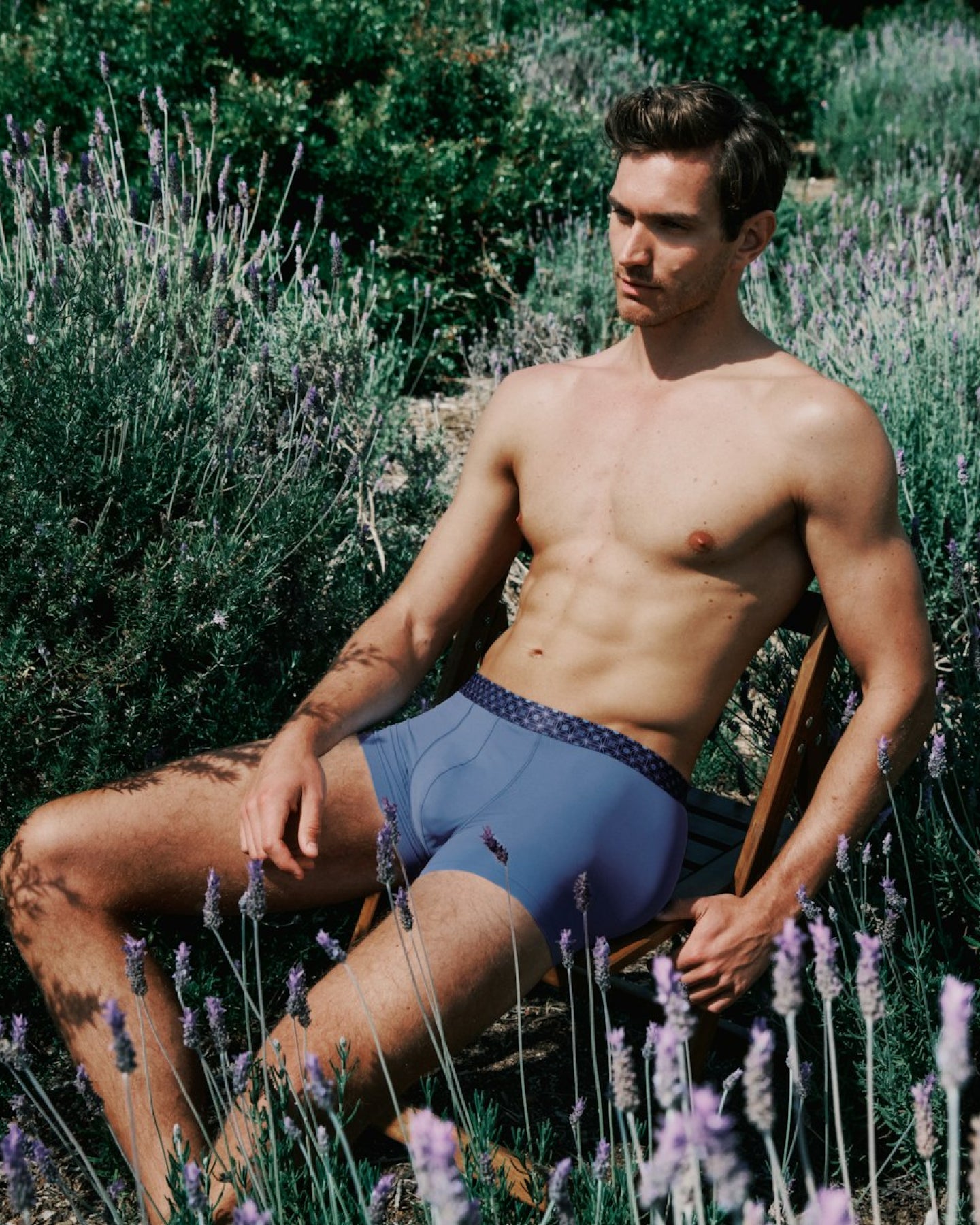 Man sitting among lavender plants wearing blue underwear